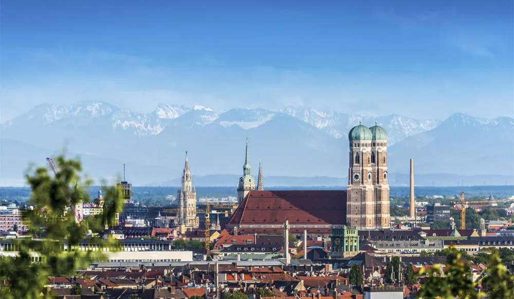 Stadt München mit Frauenkirche vor Bergkulisse